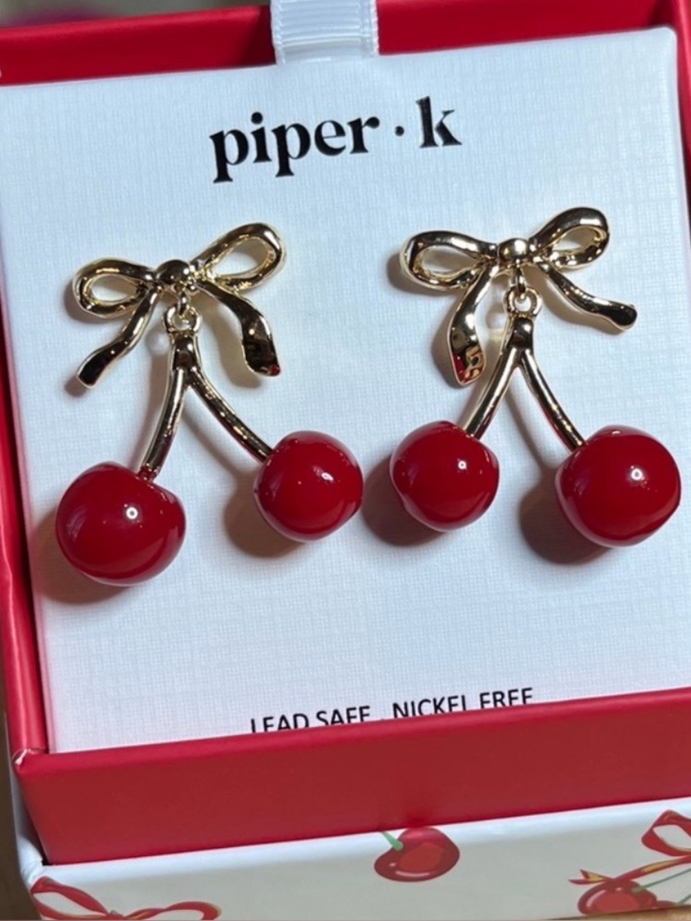 Piper•k Gold Cherry Earrings Dangling From Gold Bows